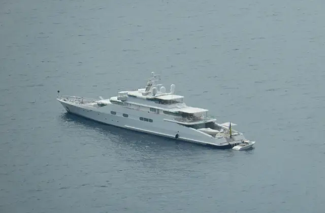 Motor boat anchored off the Capri coastline with blue water and cliffs behind