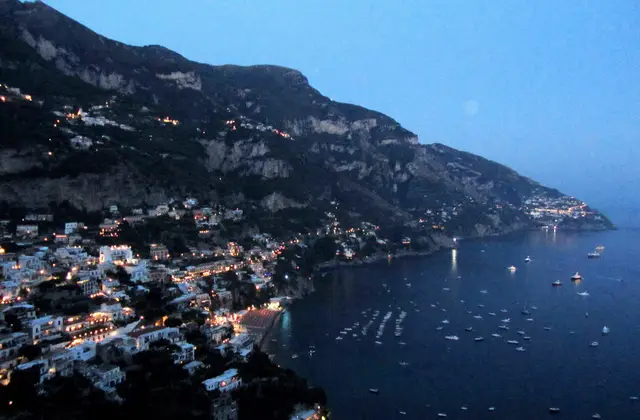 Positano lit up at night seen from the sea, with the house lights on the cliff