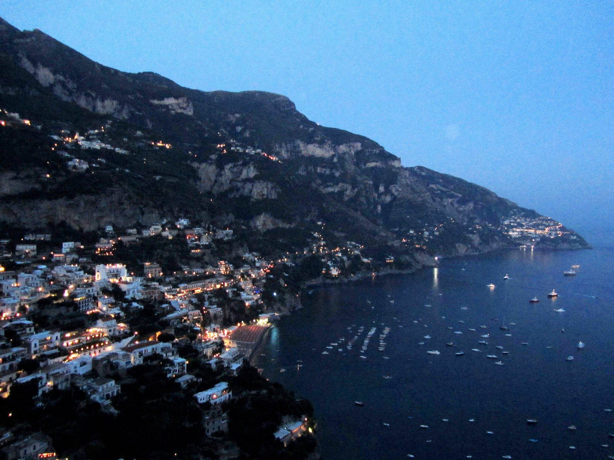 Positano lit up at night seen from the sea, with the house lights on the cliff